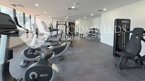 Een sportschool met diverse fitnessapparaten, waaronder loopbanden en krachtapparaten.