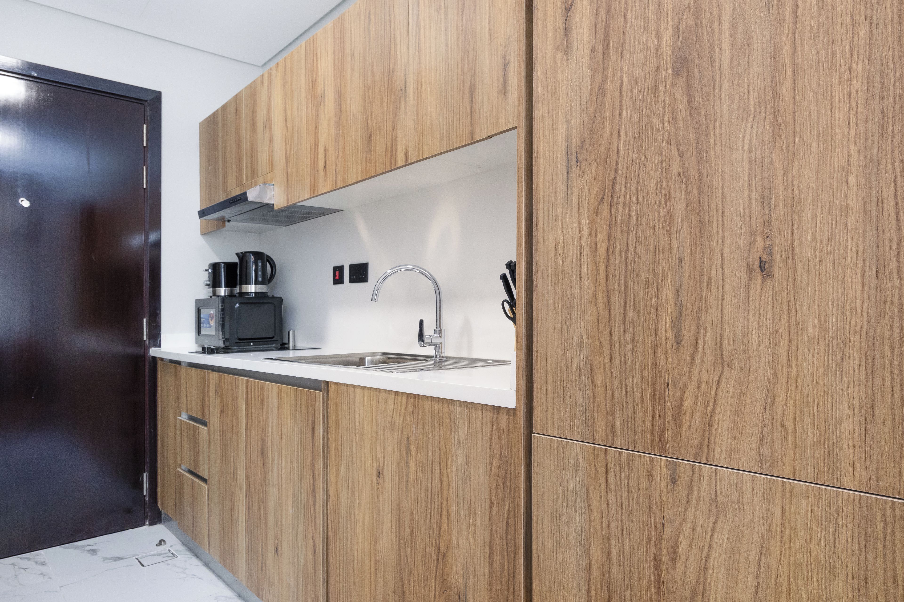 Een moderne keuken met houten kastjes, een roestvrijstalen spoelbak en een koffiezetapparaat.