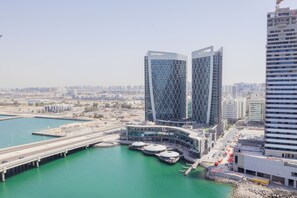 A modern building with a unique facade, situated near a waterfront with a bridge and a marina. - Bloomfeilds Hidden Gem STU Al Maryah (Abu Dhabi)