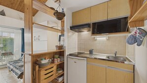 A compact kitchen with wooden cabinets, a microwave, and a dishwasher. - 50 m from the beach – apart for 2 adults / 3 children (Longeville-sur-Mer)