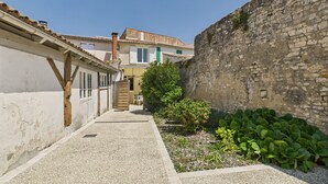 Un estrecho callejón con un muro de piedra a un lado y un edificio con techo de tejas al otro.