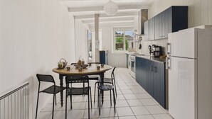 Una cocina moderna con armarios blancos, una mesa de comedor con sillas y vistas al exterior a través de una ventana.
