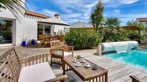 A wooden deck with outdoor furniture, a swimming pool, and surrounding greenery. - Heated pool, 800 m from the beach, villa for 8 (Noirmoutier-en-l´Ile)