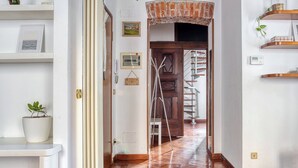 A hallway with wooden flooring, a brick archway, and a staircase leading to another level.