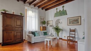 A living room with a wooden floor, a white sofa, a wooden cabinet, a white table, and a decorative chair.