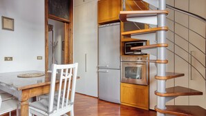 A compact kitchen with a built-in oven, a refrigerator, and a wooden cabinet.