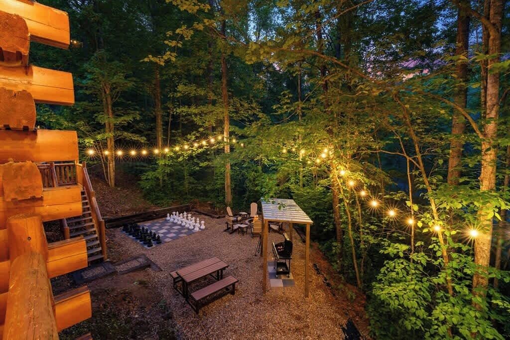 A forested outdoor area with a wooden deck, a gazebo, and a fire pit.