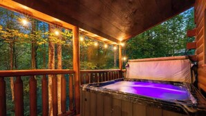 Ein Whirlpool auf einer Holzterrasse mit Blick auf einen Wald.