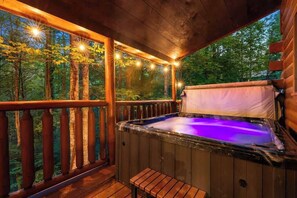A hot tub on a wooden deck with a view of a forest.