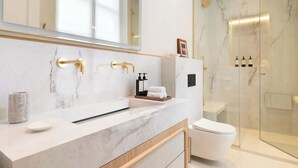 A modern bathroom with a marble vanity, a glass shower enclosure, and a white toilet.