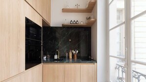A modern kitchen with wooden cabinets, a black marble backsplash, and a window with white railings.