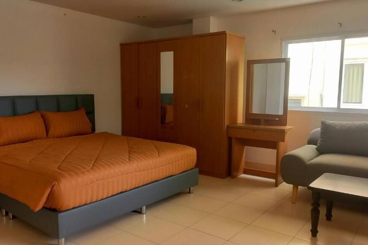 A bedroom with a bed, a wardrobe, a desk, and a sofa.