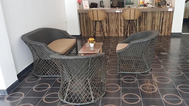 A reception area with wicker furniture, a wooden counter, and a tiled floor with circular patterns. - K2 Seaside Suites (Pattaya)