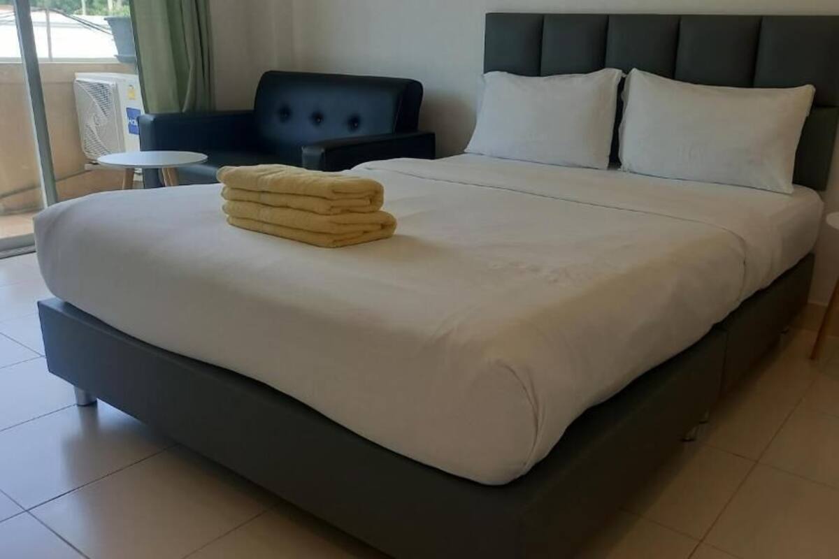 A modern hotel room with a large bed, a dark headboard, and two small round tables.
