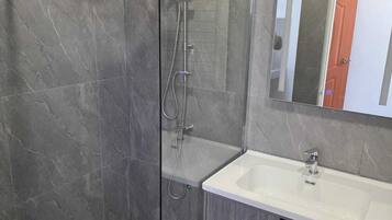 Familiekamer | Badkamer | Een douche, een haardroger, handdoeken, zeep