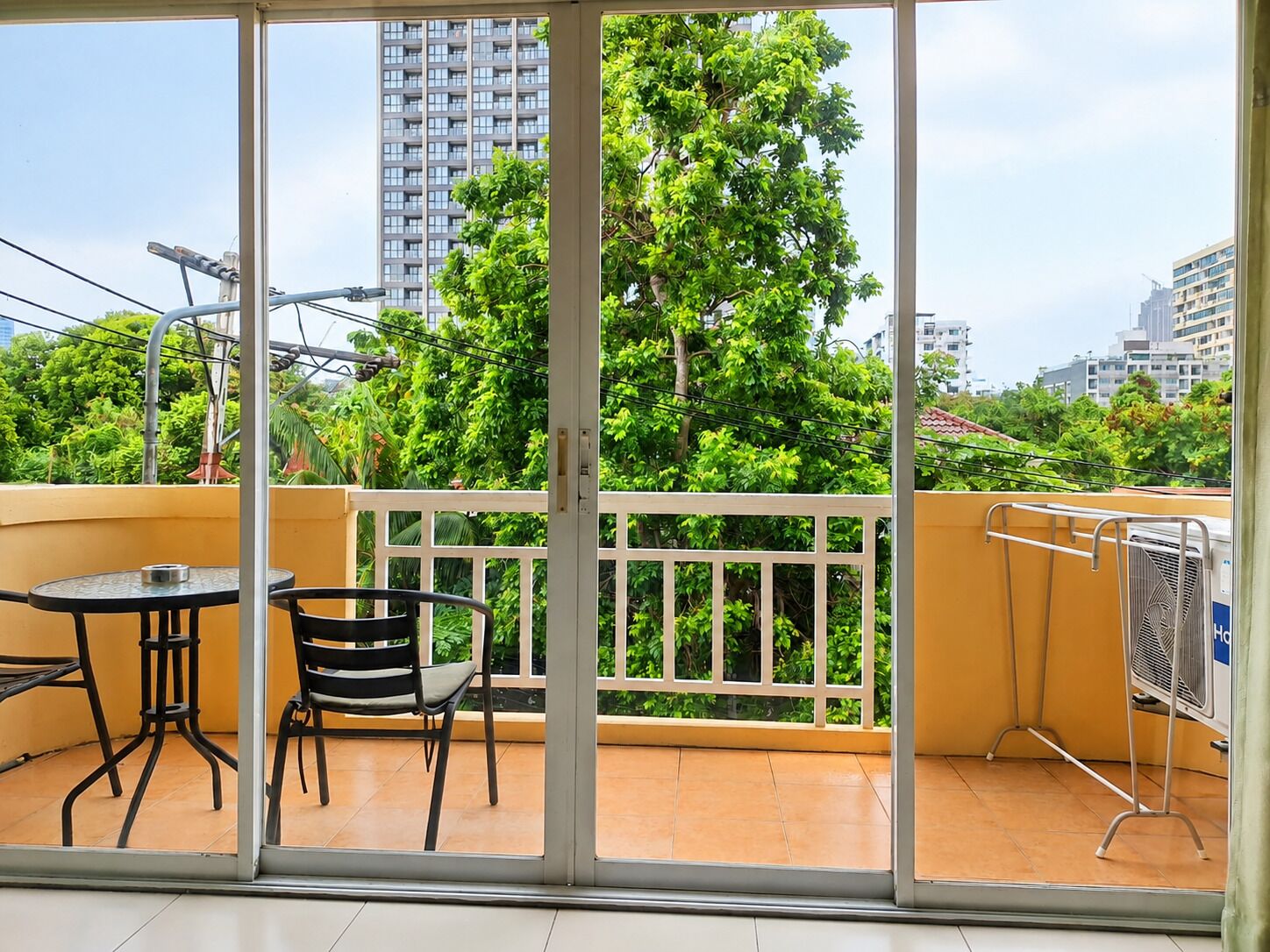 Ein Balkon mit Tisch und Stühlen, Blick auf eine Stadtlandschaft, und ein Gebäude im Hintergrund.