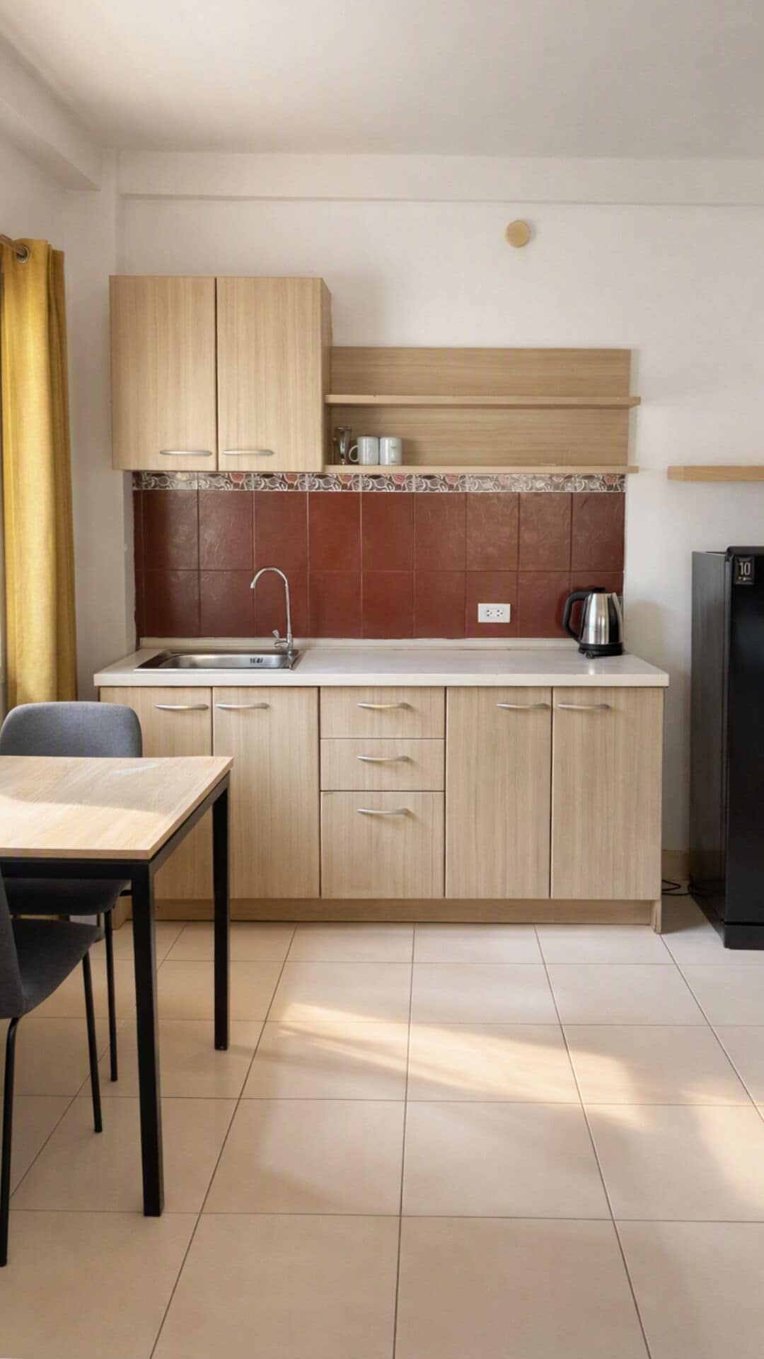 Une cuisine moderne avec des meubles de couleur bois clair, un évier en acier inoxydable et un réfrigérateur noir.