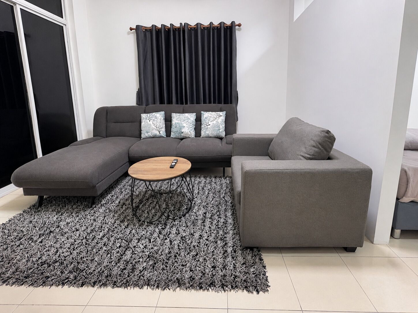 A modern living room with a grey sectional sofa, a round coffee table, and a grey rug.