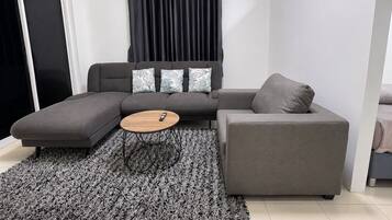 A modern living room with a grey sectional sofa, a round coffee table, and a grey rug.