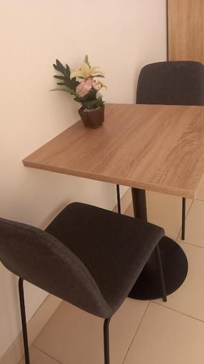 A small dining table with a wooden top and two dark chairs. - K2 Seaside Suites (Pattaya)