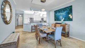 A spacious dining area with a wooden table, wicker chairs, and a large abstract painting on the wall. - REGATTA - ENJOY GULF AND BAY VIEWS! (Naples)