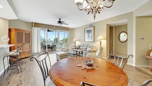 A spacious dining area with a round wooden table, surrounded by chairs, a chandelier, and a ceiling fan. - Regatta - Walk to the Beach (Naples)