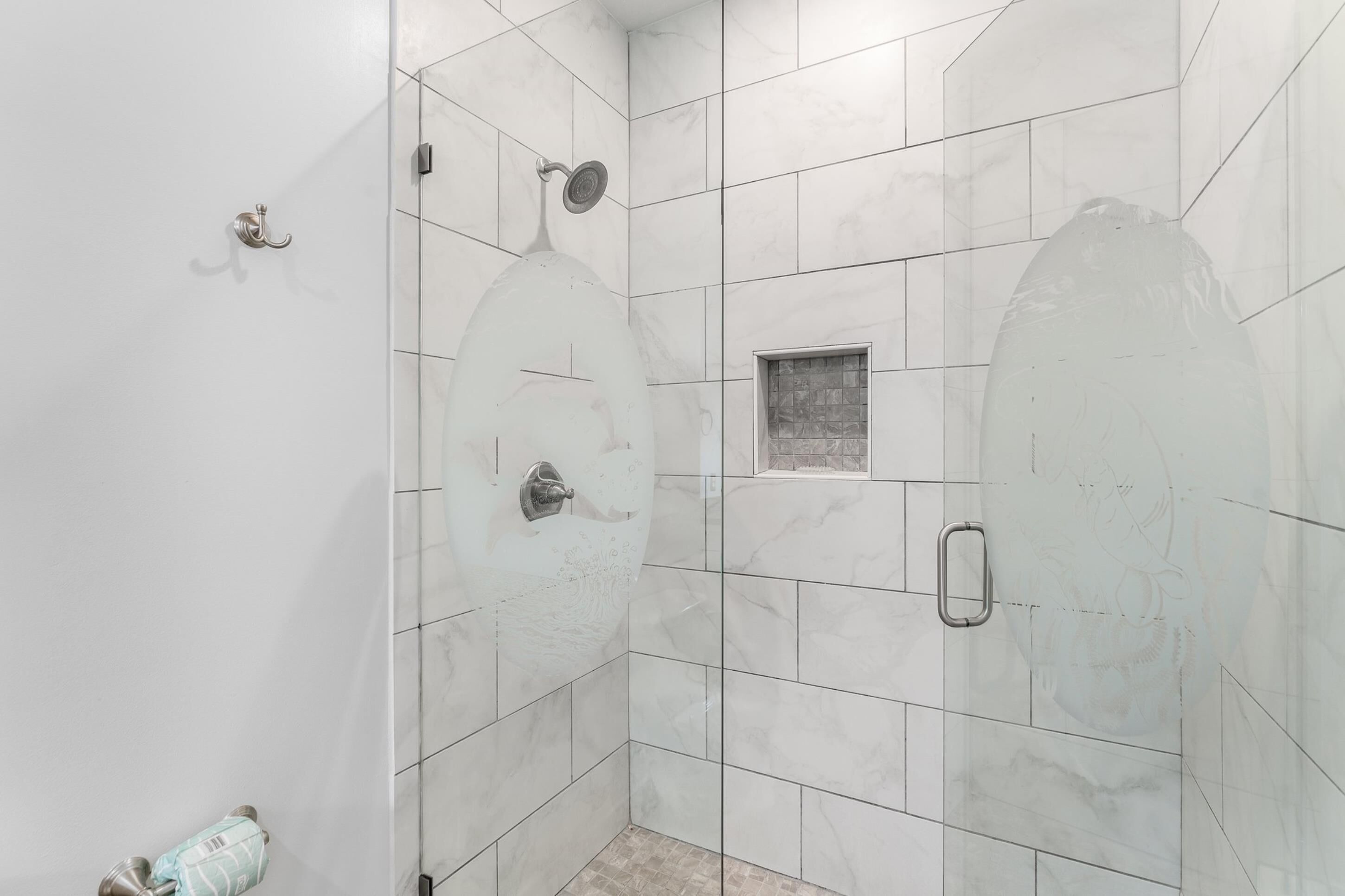 A shower area with white tiles and a small window.