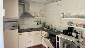 A modern kitchen with white cabinets, a built-in oven, a dishwasher, and a sink. - Seaside house in the heart of nature (Oosterend)