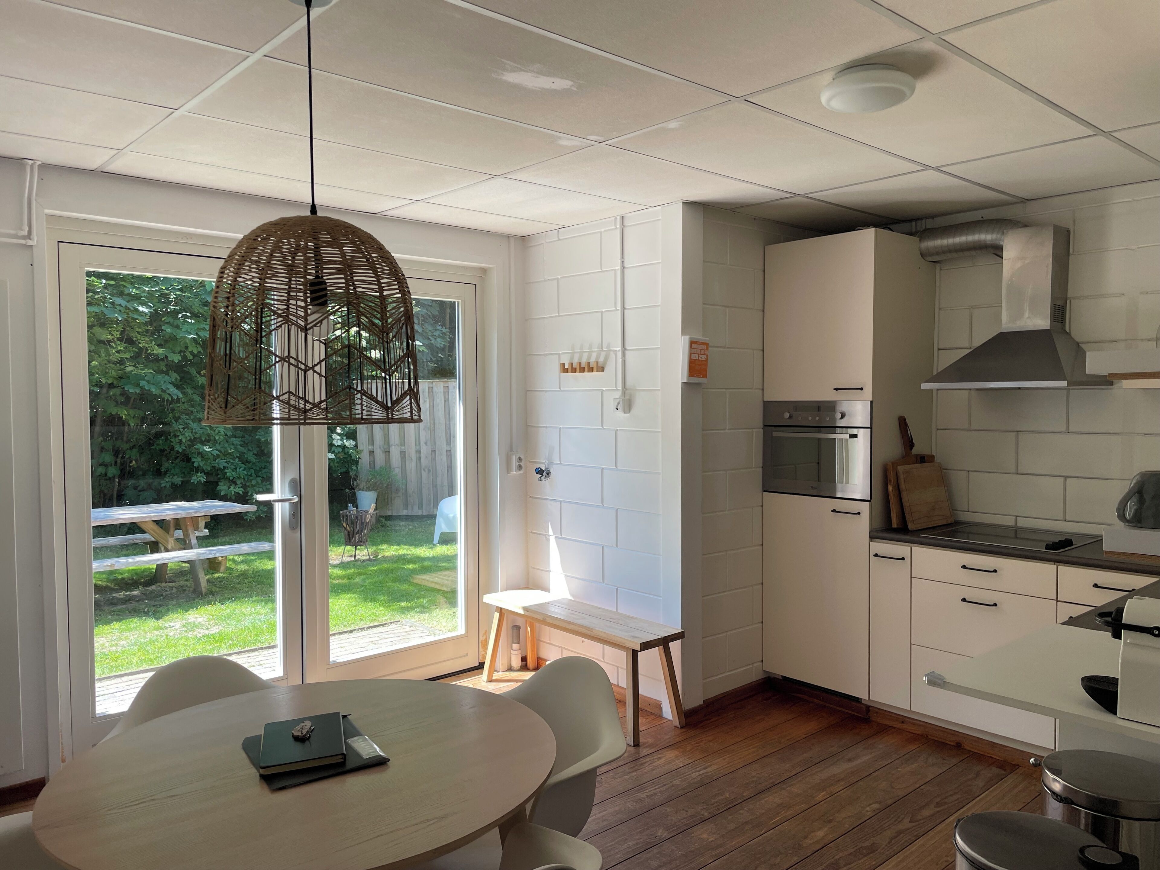 Une cuisine moderne avec des meubles blancs, un four encastré et un coin repas comprenant une table ronde et des chaises.