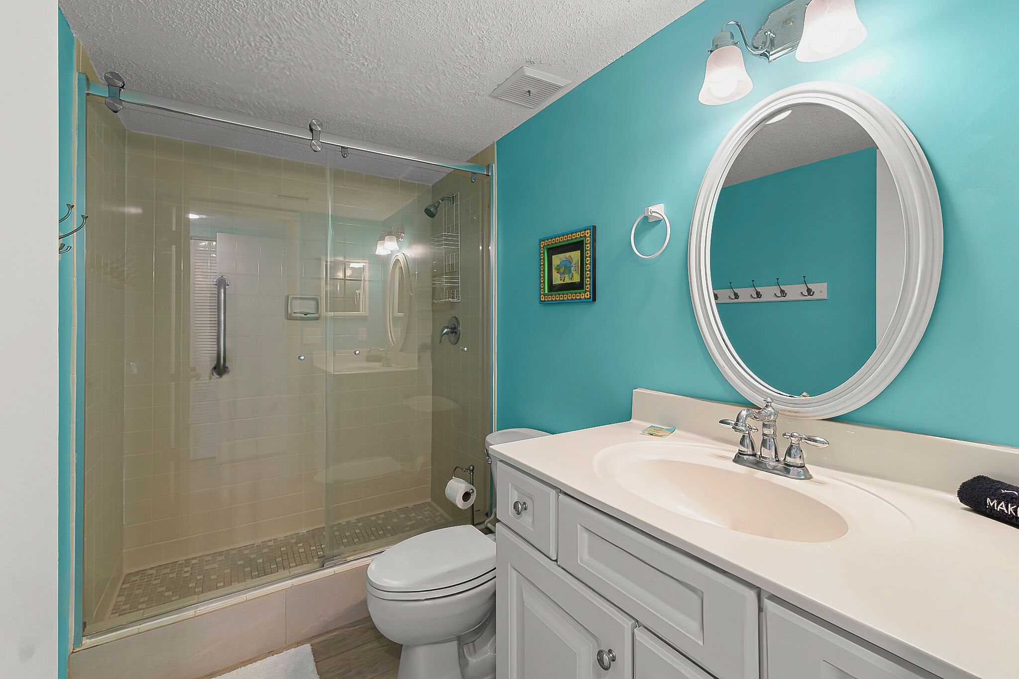 A bathroom with a glass-enclosed shower, a white toilet, a sink with a mirror, and a towel rack.