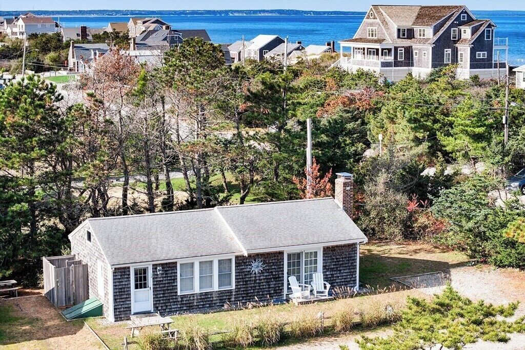 A coastal house with a sloped roof, a small porch, and a view of the ocean.