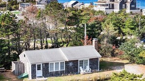 A coastal house with a sloped roof, a small porch, and a view of the ocean. - Charming Seaside Cottage  Sleeps 9 with WiFi, AC, 2 Min Walk to a Private Beach (Sandwich)