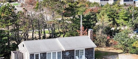 A coastal house with a sloped roof, a small porch, and a view of the ocean.