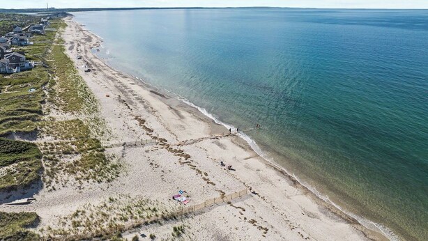A coastal beach with houses along the shore, clear blue water, and a sandy beach. - Charming Seaside Cottage  Sleeps 9 with WiFi, AC, 2 Min Walk to a Private Beach (Sandwich)