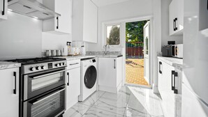 Una cocina moderna con armarios blancos, horno empotrado, lavadora y estufa.