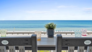 Vista de la playa con barandilla, planta en maceta y cristalería decorativa.