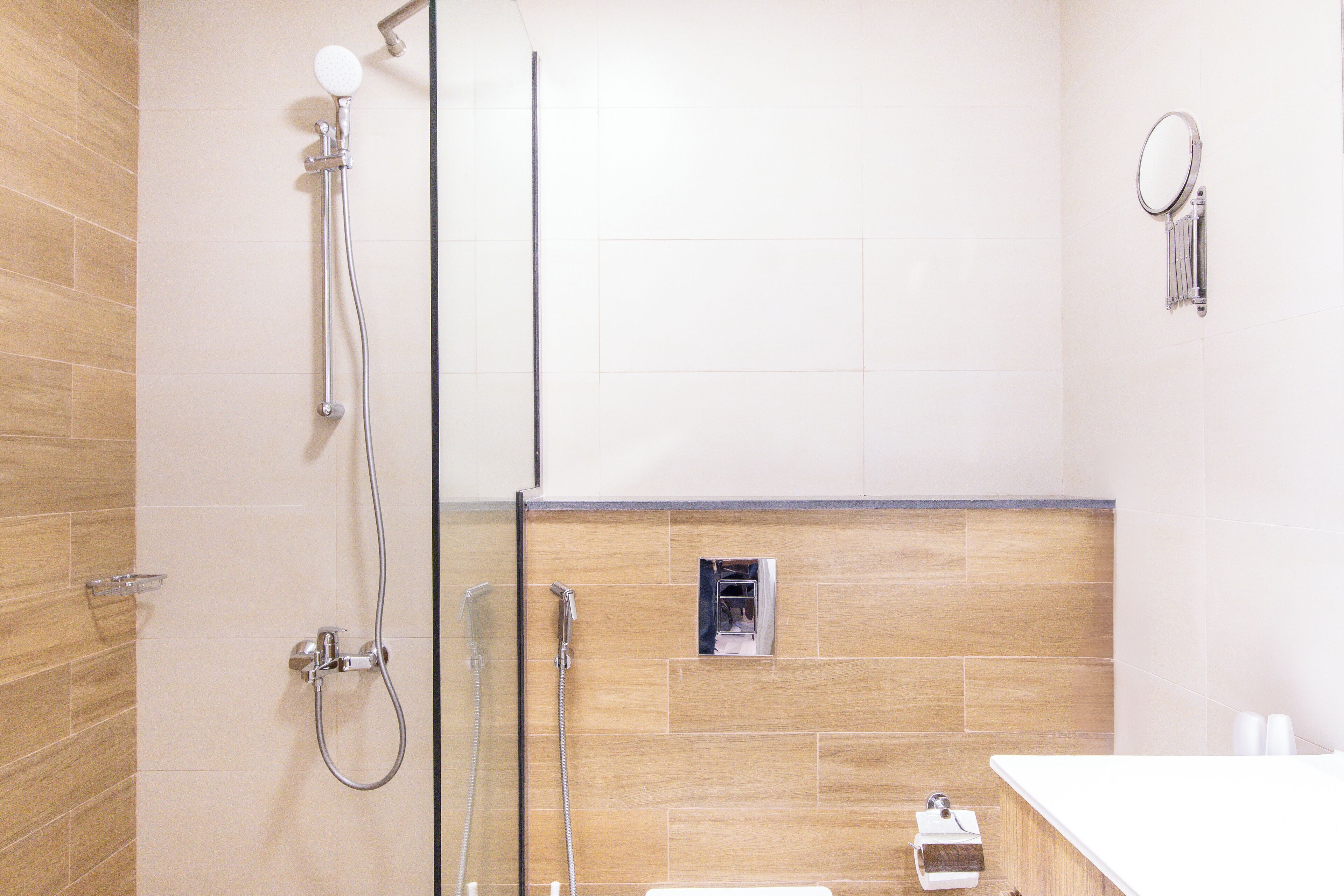 Un baño moderno con cabina de ducha de vidrio, tocador de madera y espejo.