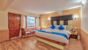 A wooden-paneled bedroom with a bed, a chair, a table, and a window with a view. - The mount Heaven Hotel  Vijayant (Manali)