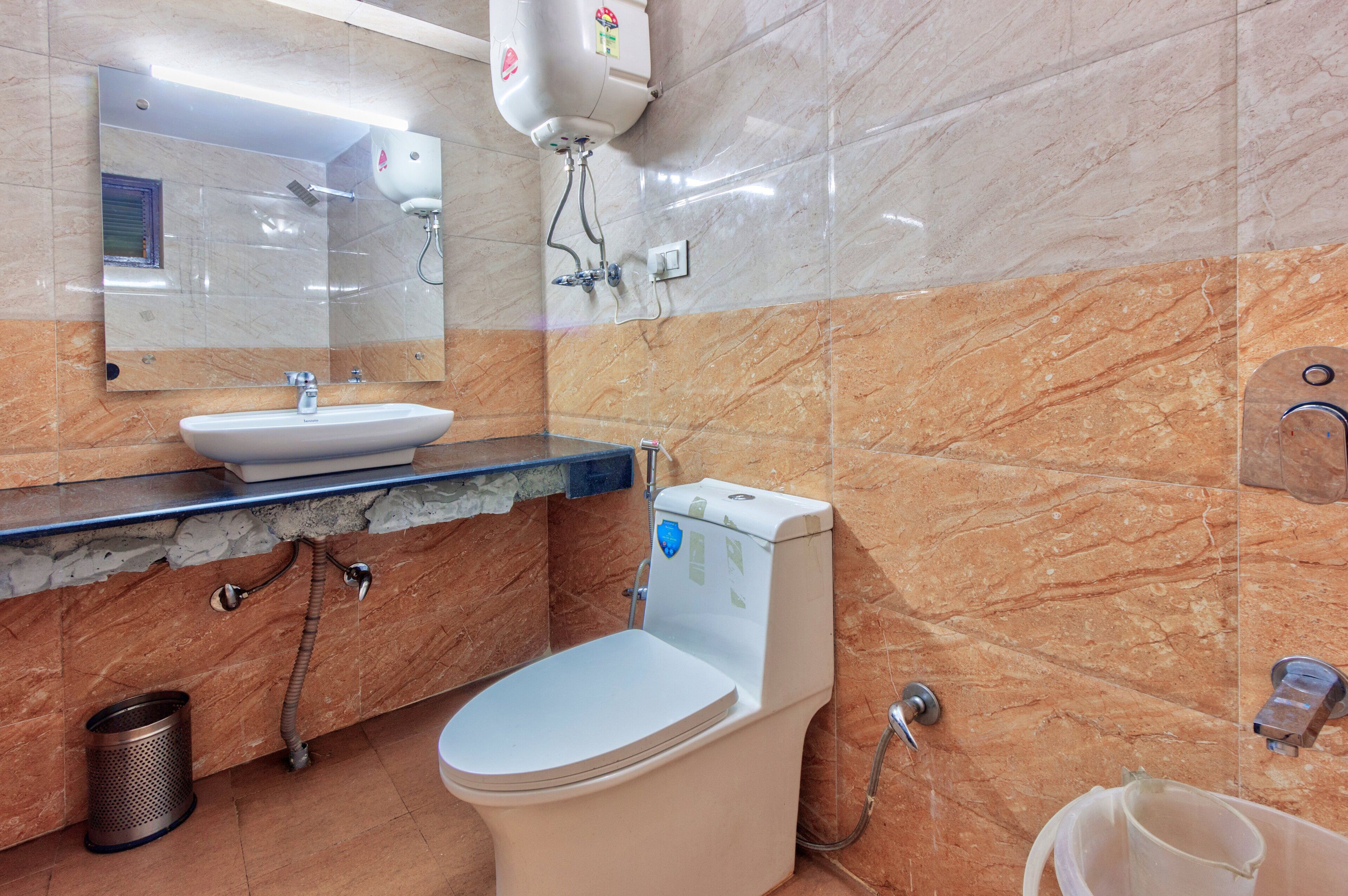 A bathroom with a marble wall, a sink, a toilet, and a mirror.