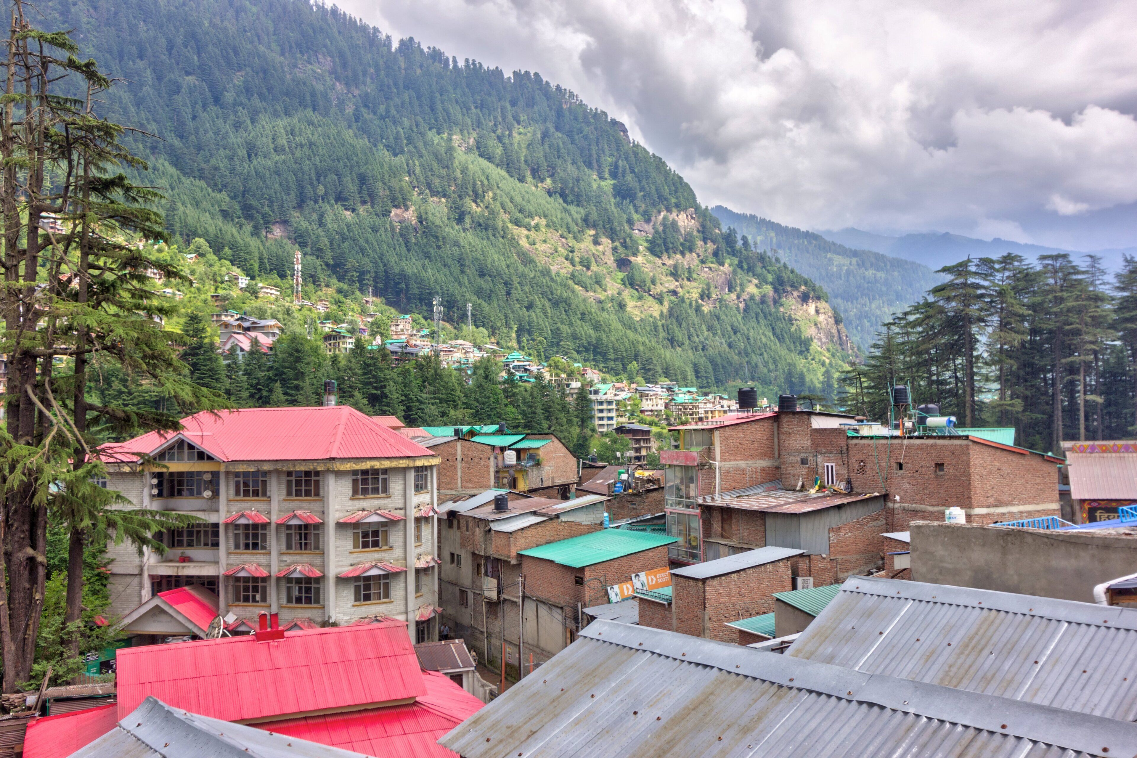Un village de montagne aux bâtiments traditionnels, avec un édifice remarquable dont le toit est de couleur rouge.
