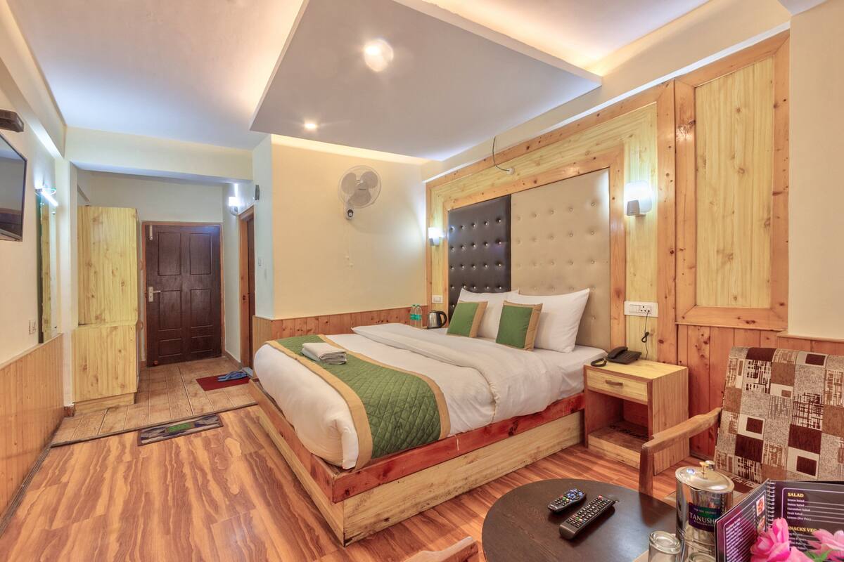 Une chambre à coucher avec un cadre en bois, comprenant un lit, une table de chevet et un petit bureau.