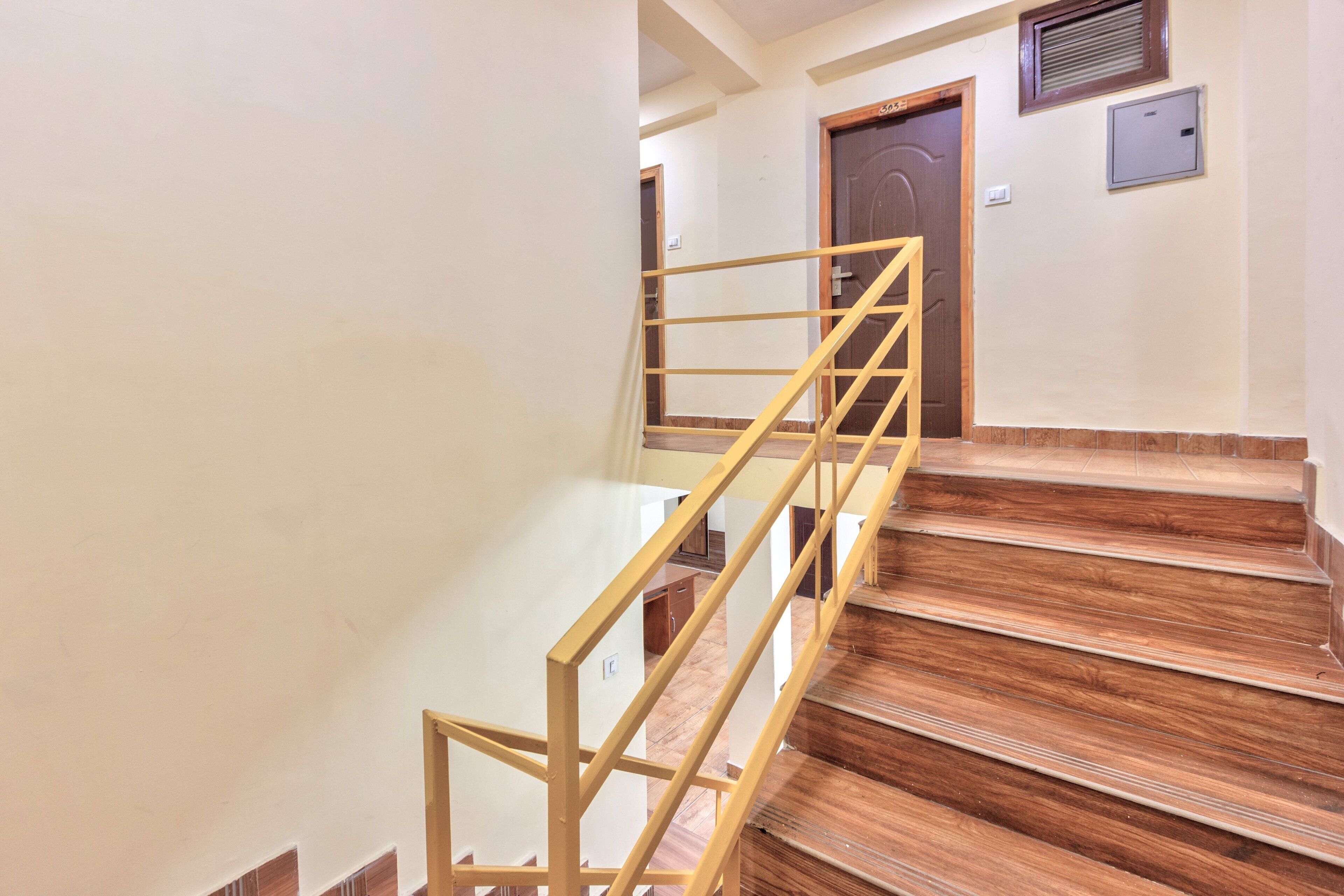 A wooden staircase with a yellow handrail leading to a door.