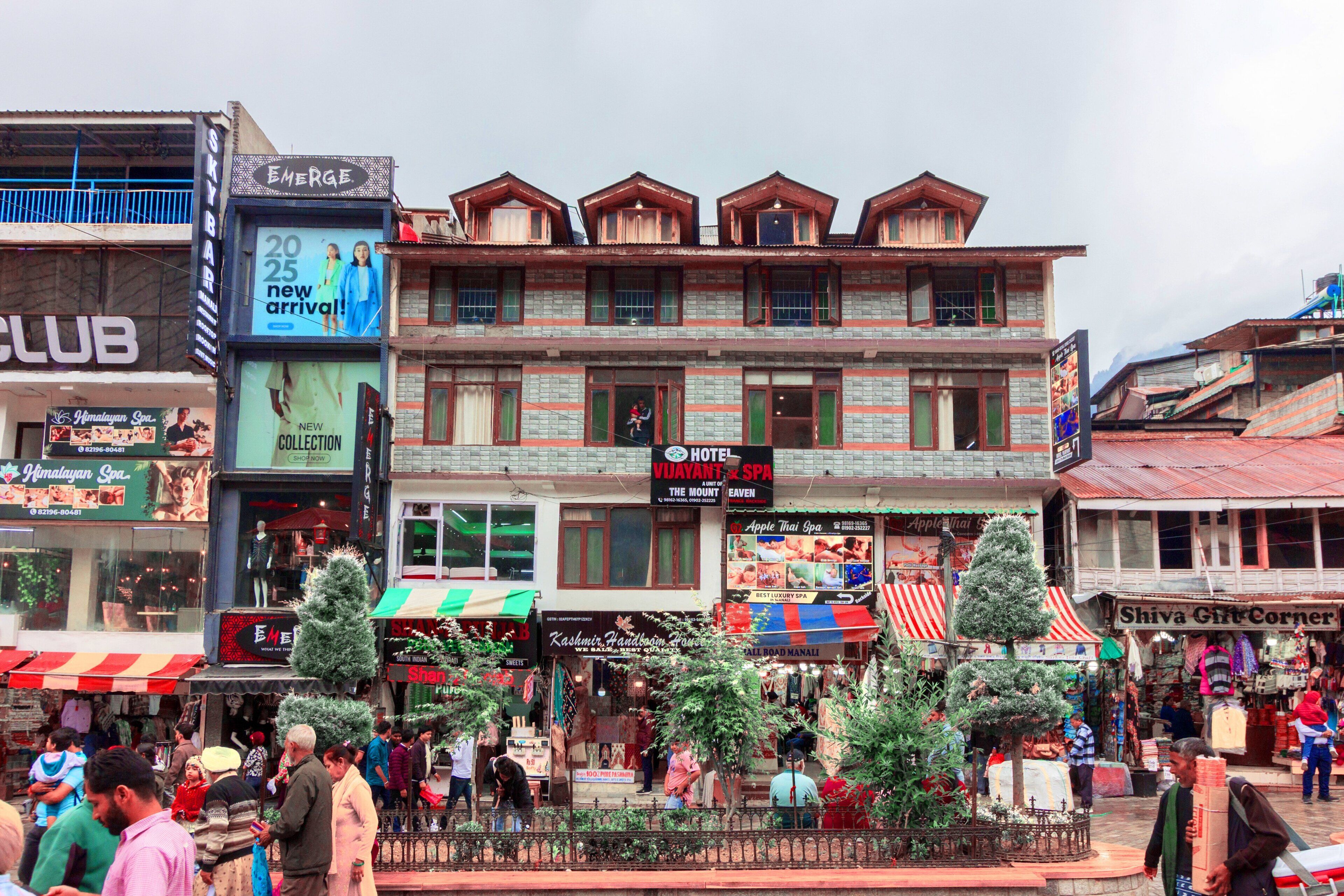 A hotel with multiple floors, balconies, and a signboard advertising a new arrival.