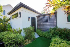 Una casa moderna con fachada blanca, valla de madera oscura y césped verde.