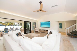 Un salon spacieux avec un canapé blanc, une table basse en bois et un ventilateur de plafond.