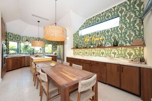 Une cuisine moderne avec une table en bois, des chaises et une grande fenêtre.