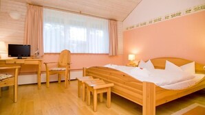 A wooden bed with white bedding, a desk with a computer, a chair, and a small table. - Hotel Haus Linden (Ostseebad Prerow)