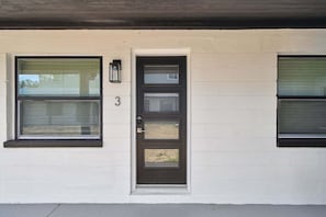 Stylish single-story residence with a dark brown front door and three windows.