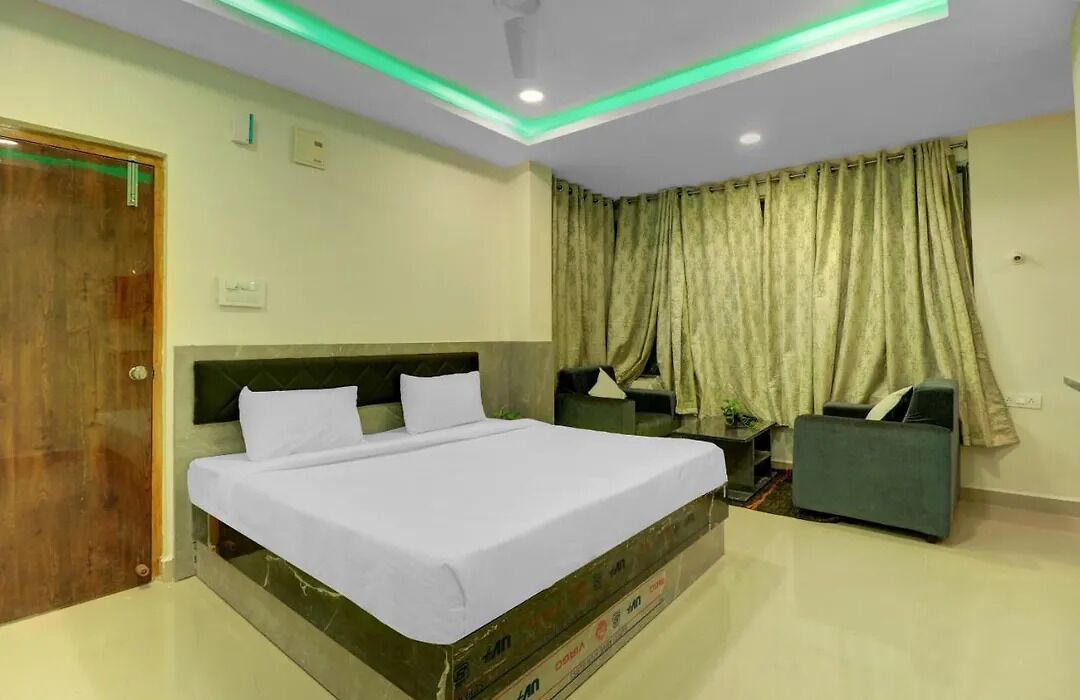 A hotel room with a bed, a sofa, a curtain, and a ceiling light.
