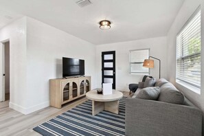 Relax in this stylish living room with a flat-screen TV, round coffee table, and comfortable sofa.